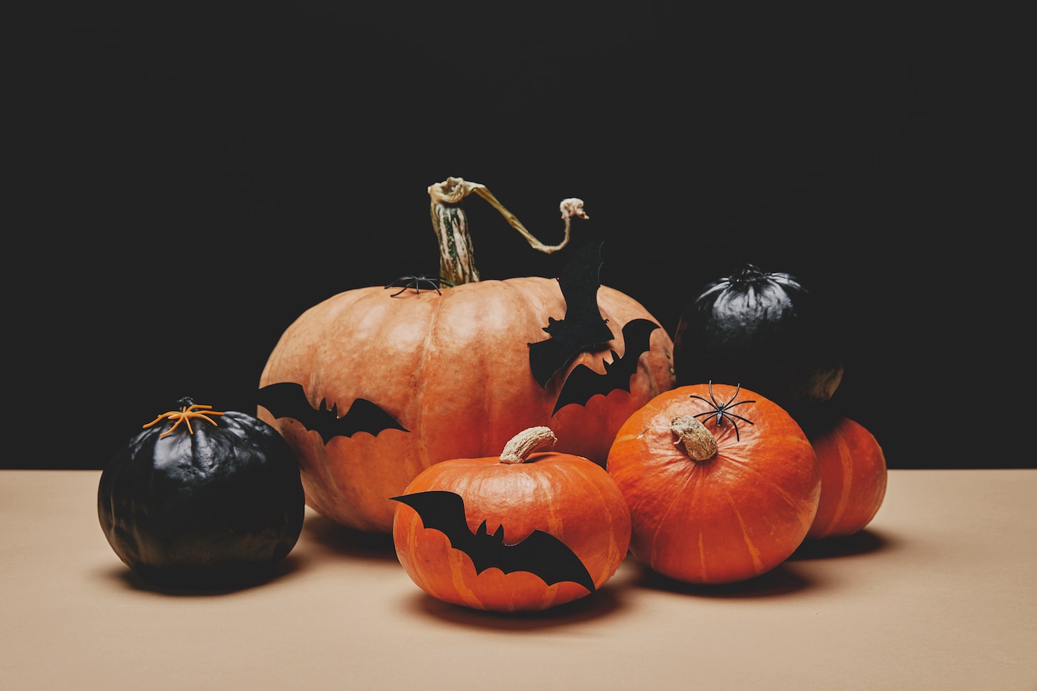 Halloween scene with black and orange punpkins decorated with paper bats.