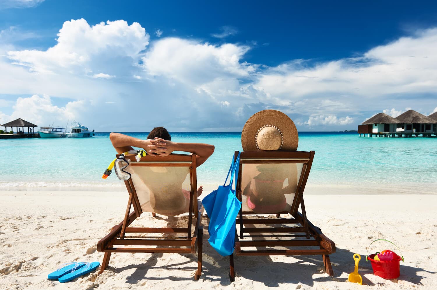 A man and woman sitting on beach chairs looking towards the ocean.