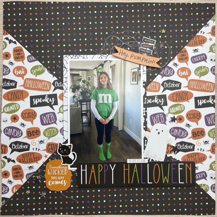 A Halloween themed scrapbook page with the title Happy Halloween and a young girl dressed as a green M-n-M.